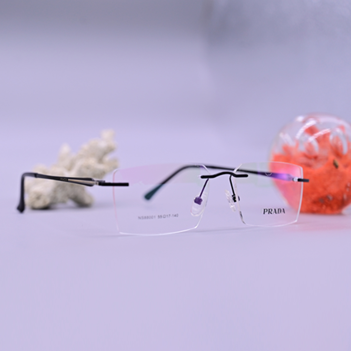 نظارة طبية فاخرة من ماركة برادا موديل 88001، تصميم بدون إطار (Rimless) بجسر وأذرع معدنية باللون الأسود مع لمسات أرجوانية (موف)، متوفرة في متجر عين العون.