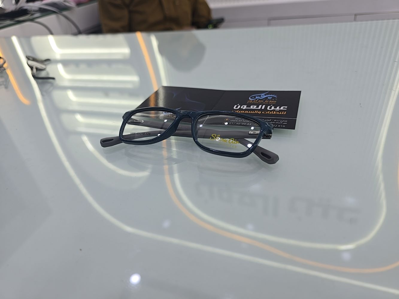 نظارة أطفال طبية ماركة شو آين موديل 1009، إطار دائري كامل بلون أزرق داكن مطفي وأذرع رمادية، متوفرة في متجر عين العون.