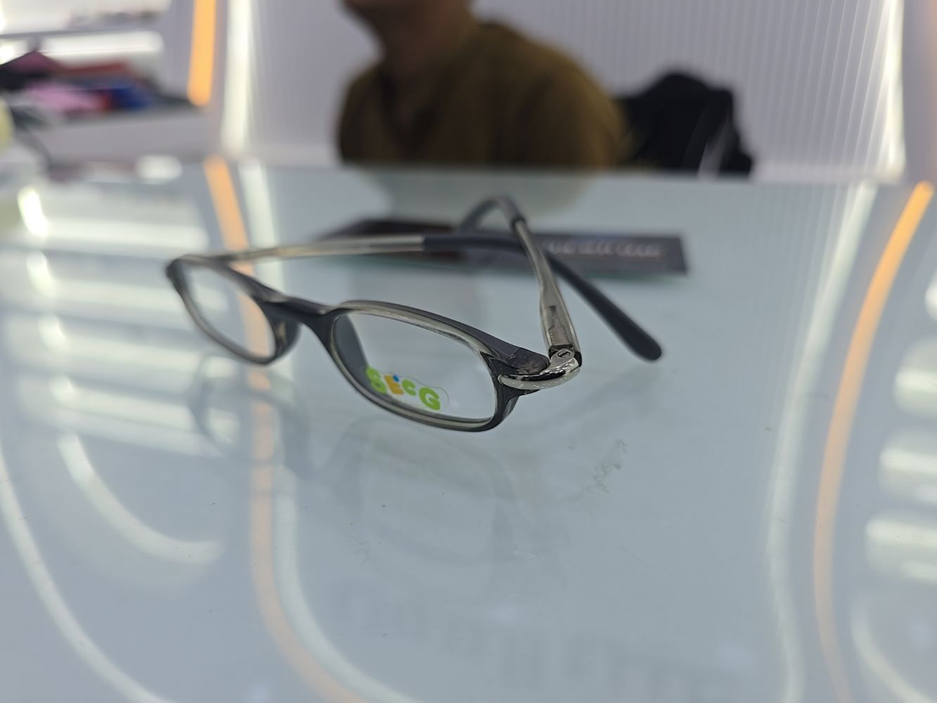 نظارة أطفال طبية من ماركة سيج (Secg) موديل 5557، تتميز بإطار دائري كامل بلون رمادي شفاف ولامع، متوفرة لدى متجر عين العون للبصريات.