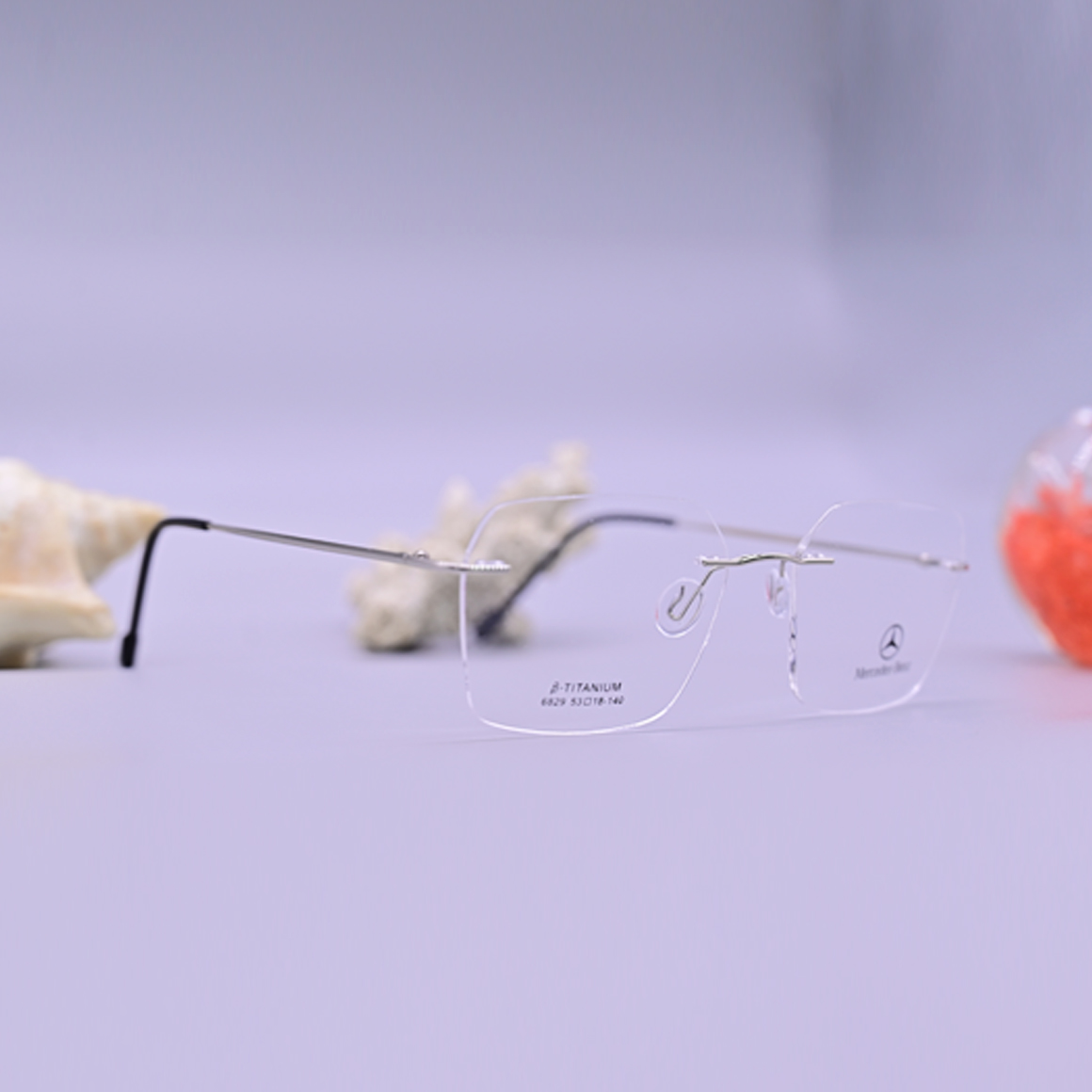 نظارة طبية ماركة مرسيدس بنز موديل 6829، تصميم بدون إطار (Rimless) بجسر وأذرع معدنية فضية نحيفة مع نهايات سوداء مريحة، متوفرة لدى متجر عين العون للبصريات.