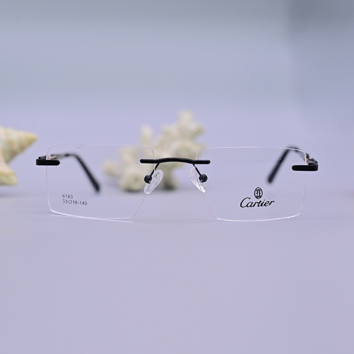 نظارة طبية فاخرة ماركة كارتير موديل 6183، تصميم بدون إطار (Rimless) بجسر وأذرع سوداء مع لمسات فضية عند المفصلات، متوفرة لدى متجر عين العون للبصريات.