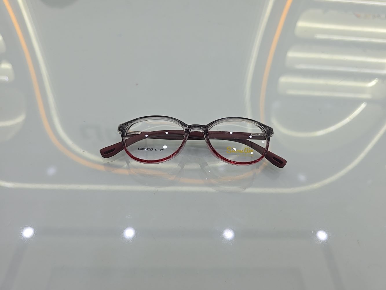 نظارة أطفال طبية ماركة شو آين موديل 1002، إطار دائري كامل بلون عنابي (برغندي) متدرج ومنقط من الأعلى، متوفرة في متجر عين العون.