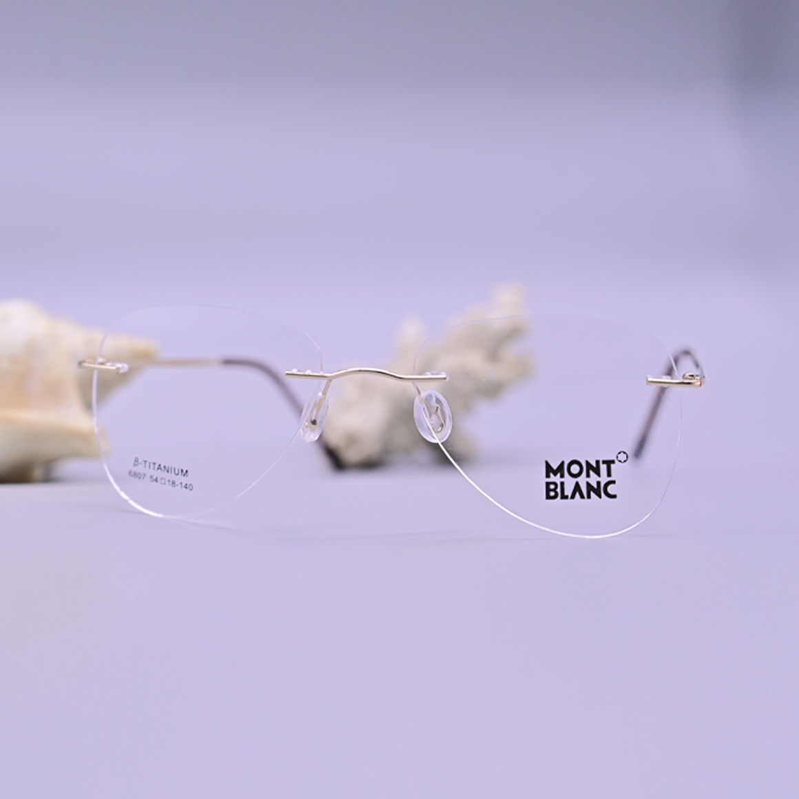 نظارة طبية فاخرة ماركة مونت بلانك موديل 6807، تصميم بدون إطار (Rimless) بجسر وأذرع معدنية ذهبية ونهايات بنية داكنة، متوفرة لدى متجر عين العون للبصريات.